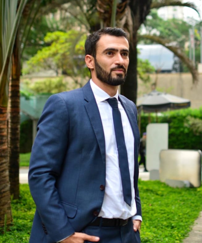 Leonardo Carvalho Tenório ao ar livre, de terno azul, com a mão no bolso